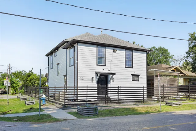 a view of a house with a small yard and large tree