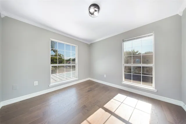 an empty room with wooden floor ceiling fan and windows