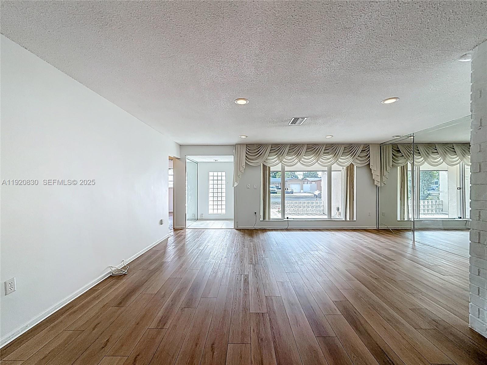 7541 Embassy Boulevard Miramar, FL 33023 - Photo 11 of 60 a view of an empty room with wooden floor and a window