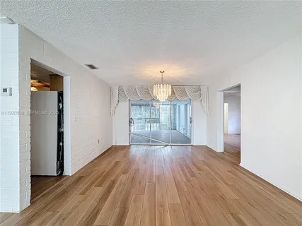 a view of an empty room with wooden floor and a ceiling fan