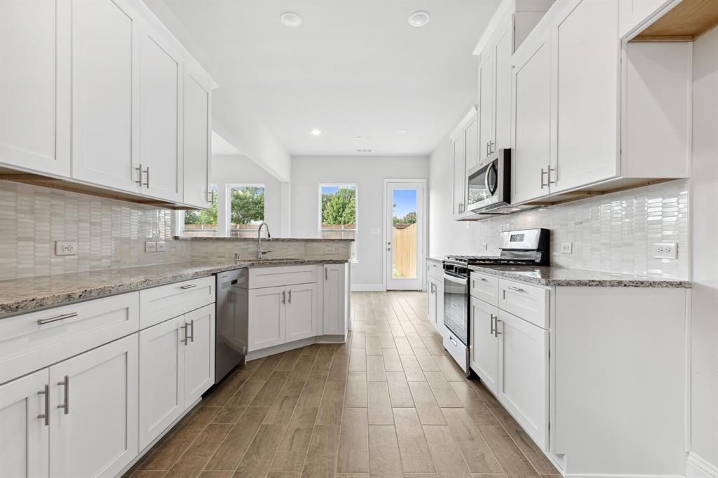 a kitchen with granite countertop white cabinets white stainless steel appliances a sink and dishwasher