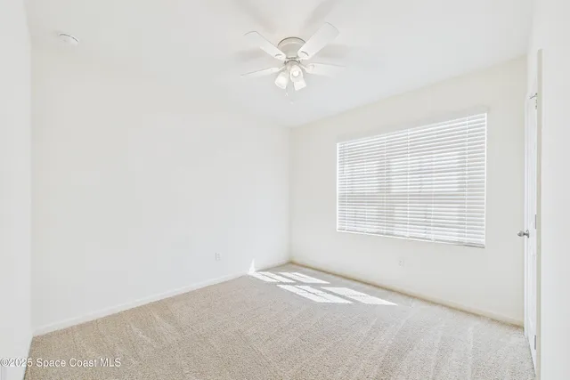 an empty room with a ceiling fan and a window