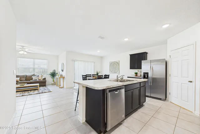 a kitchen with stainless steel appliances a stove a sink a microwave a refrigerator white cabinets and wooden floor