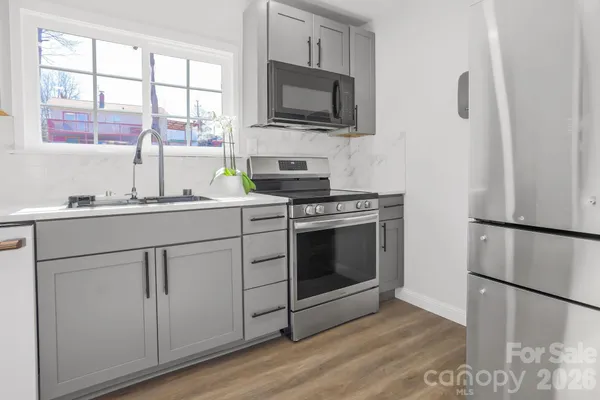 a kitchen with cabinets stainless steel appliances a sink and a window
