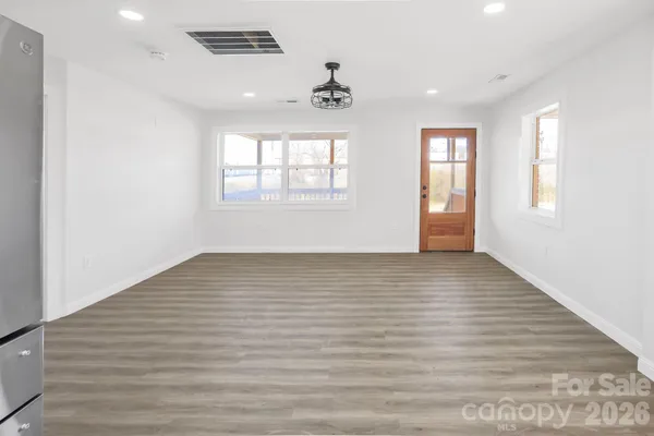 an empty room with wooden floor and windows