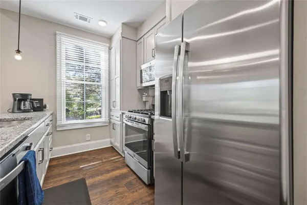 a kitchen with stainless steel appliances granite countertop a sink a stove and a wooden floor