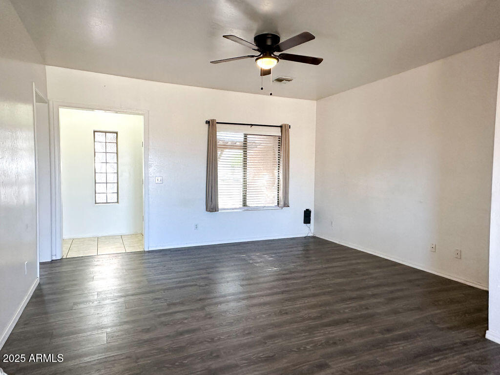 15220 Padres Road Arizona City, AZ 85123 - Photo 3 of 16 an empty room with wooden floor chandelier fan and windows