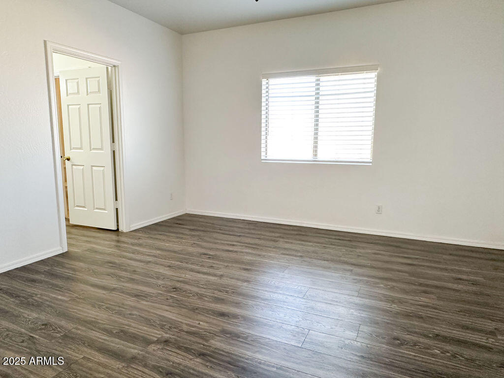 15220 Padres Road Arizona City, AZ 85123 - Photo 10 of 16 an empty room with wooden floor and windows