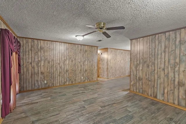 an empty room with wooden floor closet and windows