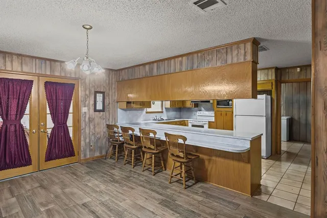 a kitchen with stainless steel appliances granite countertop a refrigerator a sink dishwasher a dining table and chairs with wooden floor