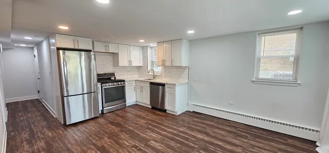 a kitchen with granite countertop stainless steel appliances a refrigerator cabinets and wooden floor