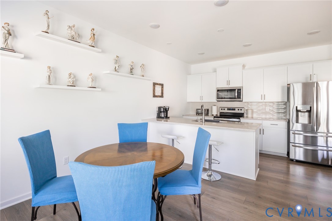 11309 Benton Pointe Way Chester, VA 23831 - Photo 12 of 32 a kitchen with white cabinets stainless steel appliances and dining table