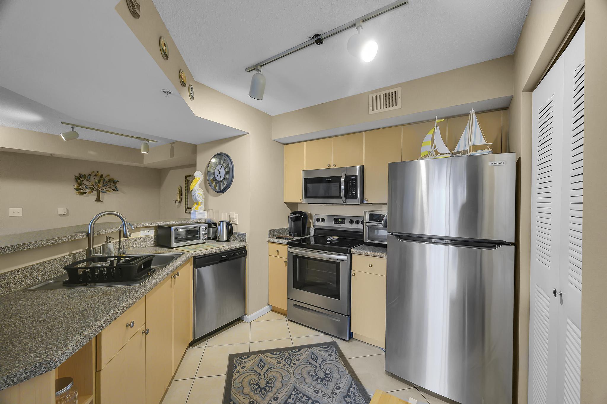 3670 Northwest Adriatic Lane Jensen Beach, FL 34957 - Photo 4 of 26 a kitchen with a refrigerator a stove a sink a microwave and cabinets