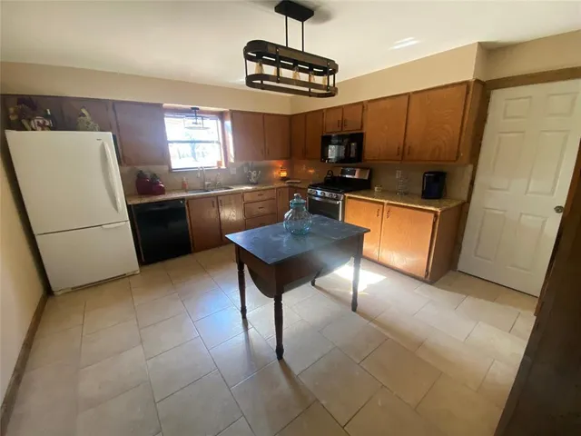 a kitchen with stainless steel appliances granite countertop a refrigerator a sink a stove a dining table and chairs with wooden floor