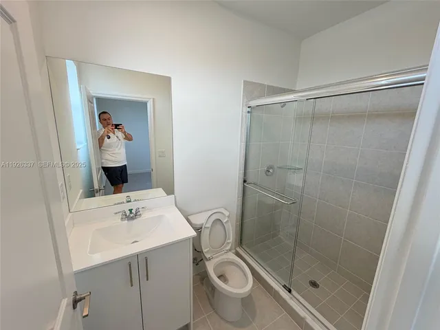 a bathroom with a shower sink vanity and toilet