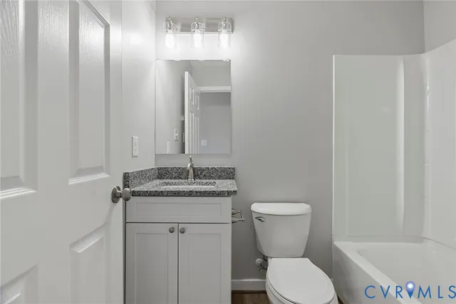 a bathroom with a granite countertop toilet sink and mirror