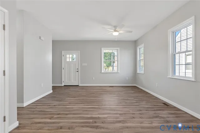 an empty room with wooden floor and windows