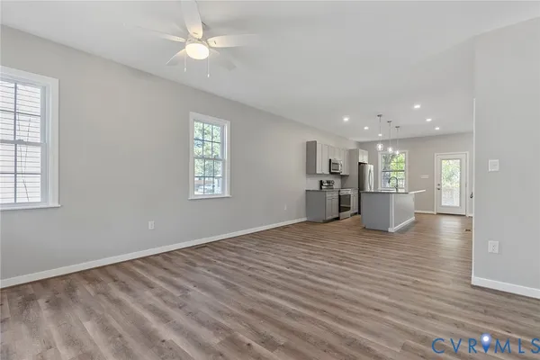 a view of empty room with wooden floor and kitchen view