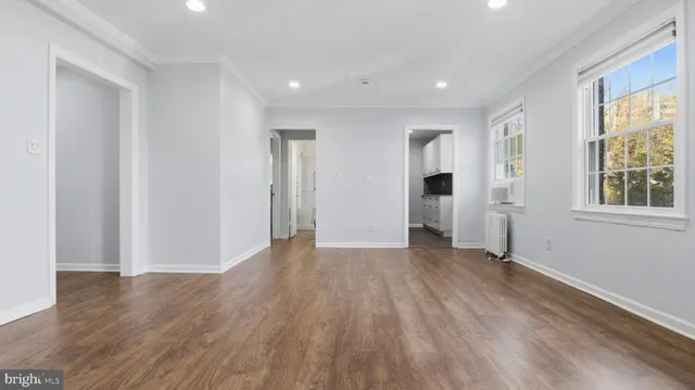 a view of an empty room with wooden floor and windows