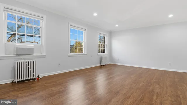 a view of an empty room with a window and wooden floor