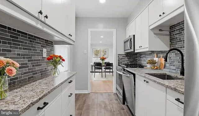 a kitchen with granite countertop a stove a sink and a wooden cabinets