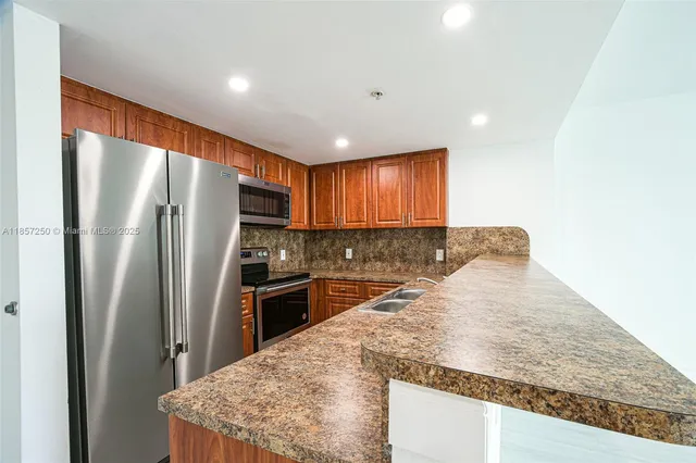 a kitchen with stainless steel appliances granite countertop refrigerator sink and stove