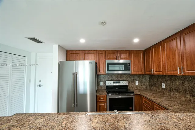 a kitchen with stainless steel appliances granite countertop a refrigerator stove and sink