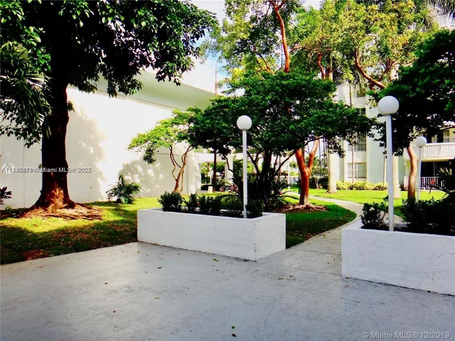 a view of a patio with table and chairs potted plants and a large tree