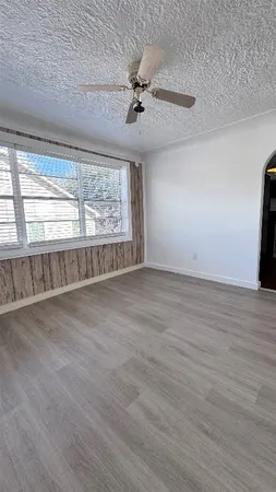 an empty room with wooden floor fan and windows