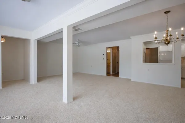 an empty room with chandelier fan and windows