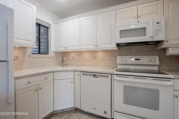 a kitchen with white cabinets and white appliances