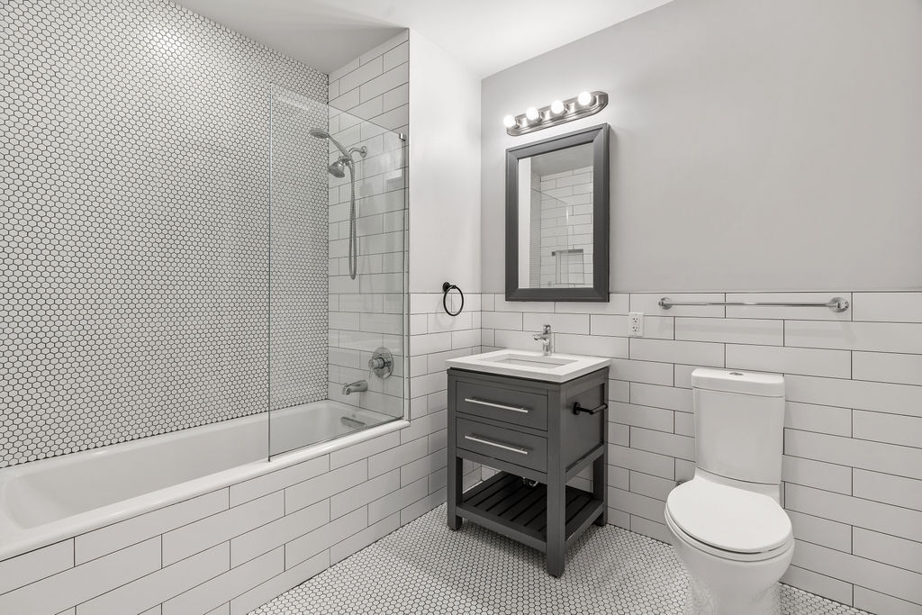 Undisclosed Address Queens, NY 11101 - Photo 18 of 21 a bathroom with a toilet a sink a mirror and bathtub