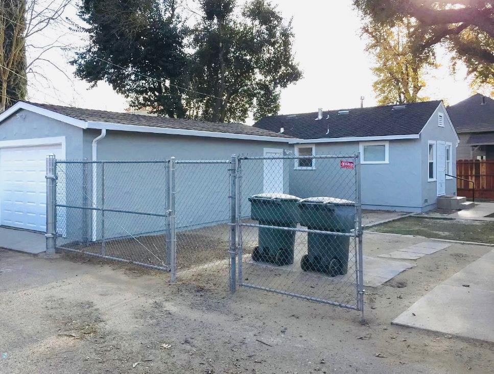 612 16th Street Modesto, CA 95354 - Photo 10 of 19 view of back home with a gate, stucco siding, and a detached garage. Note * Photos are not current photos. Both front and back units occupied, do not disturb.