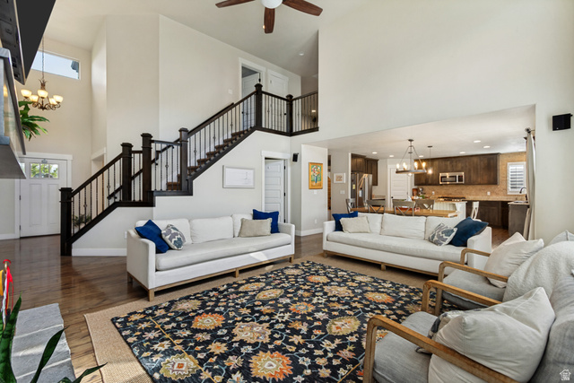 Vaulted ceilings with a ceiling fan, wood-finish flooring, staircase with dark wood newel posts and balusters, open concept kitchen, and upper transom windows