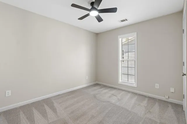 an empty room with windows and fan