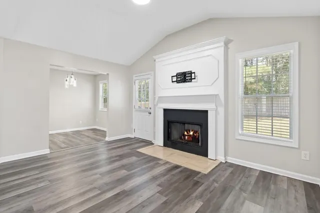 a view of an empty room with wooden floor fireplace and a window
