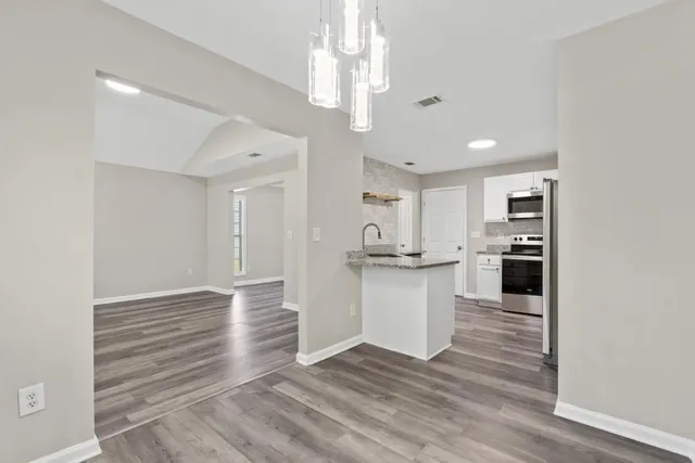 a view of kitchen with granite countertop cabinets and refrigerator