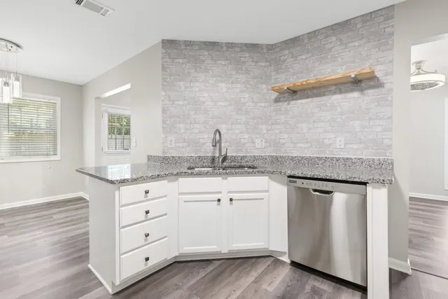 a kitchen with granite countertop a sink cabinets and wooden floor