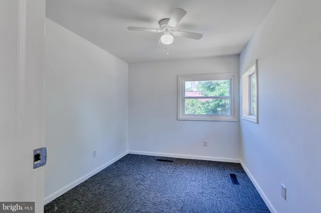 an empty room with a window and a ceiling fan