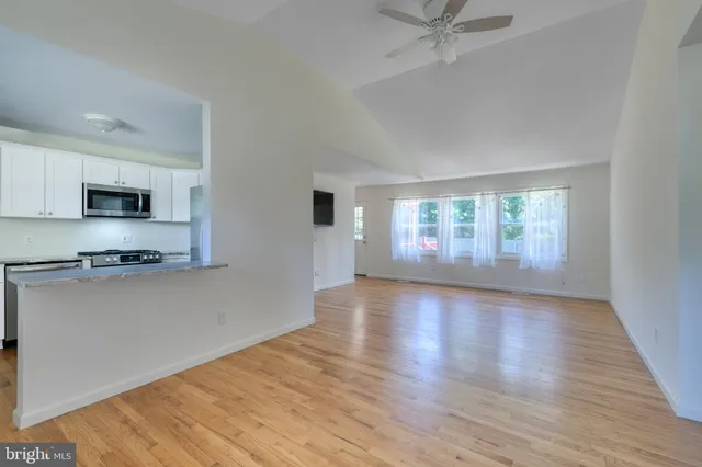 a view of an empty room with a window and wooden floor