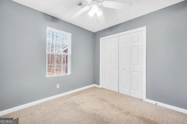 an empty room with a window and ceiling fan