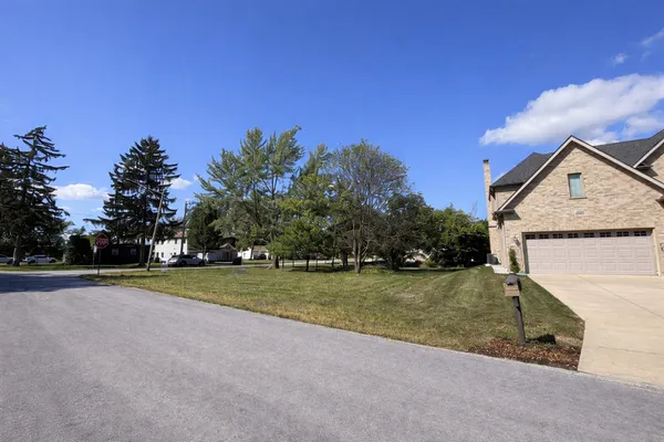 a view of a house with a big yard and large trees