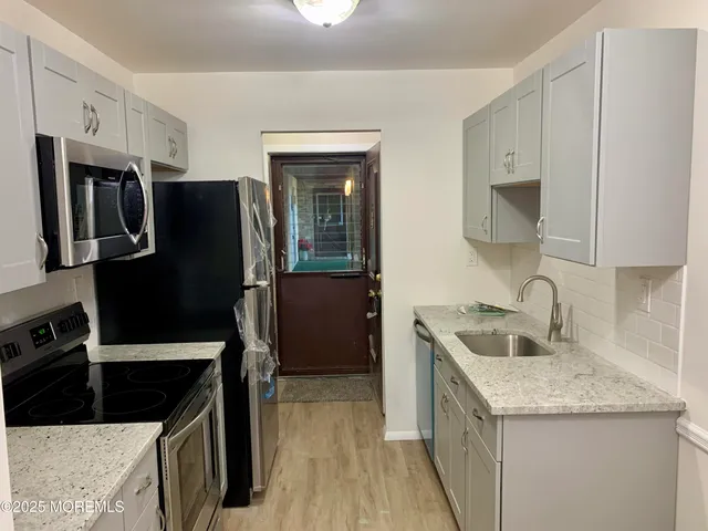 a kitchen with granite countertop a refrigerator stove and sink