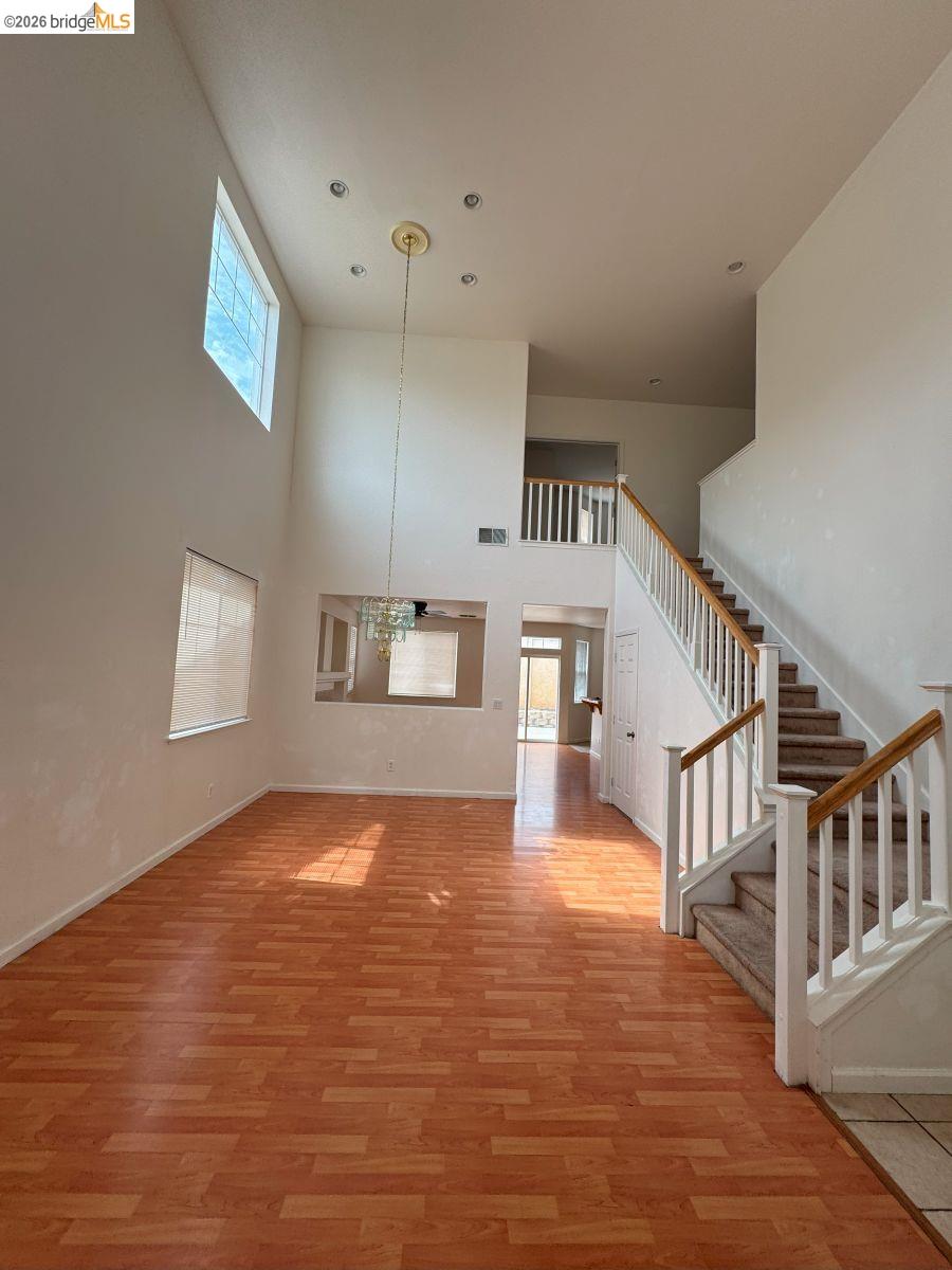 645 Rockspray Circle Pittsburg, CA 94565 - Photo 28 of 31 Unfurnished living room with light wood-style flooring, a towering ceiling, stairway, a chandelier, and recessed lighting