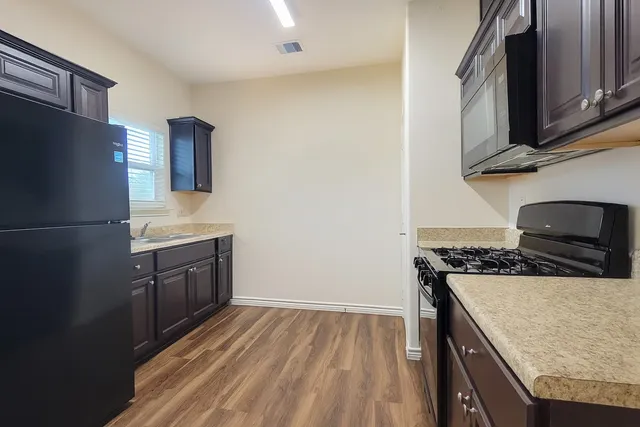 a kitchen with a sink stove top oven and refrigerator