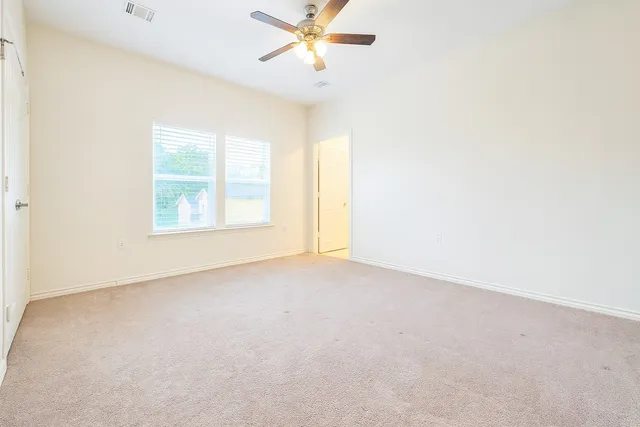an empty room with windows and fan