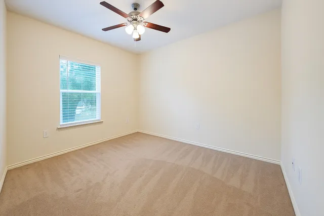 an empty room with windows and fan