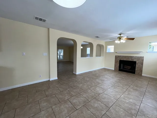 an empty room with windows and fireplace