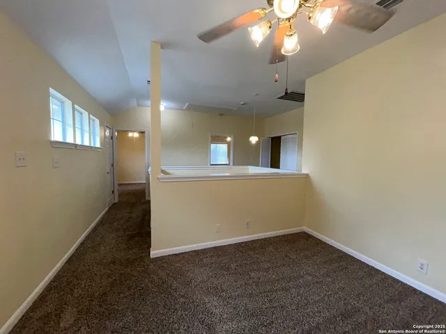 en empty room with a chandelier fan and windows