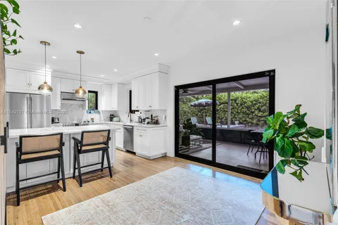 a living room with furniture a potted plant and kitchen view
